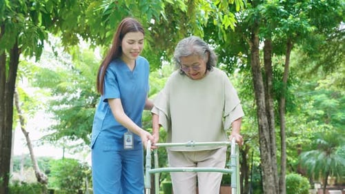Caregiver Assists Senior Woman with Walker in Park