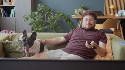 Man Relaxing on Couch with Dog and Smartphone