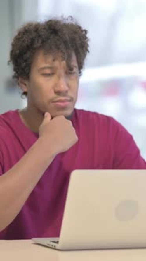 Young Man Works on Laptop at Desk Indoors