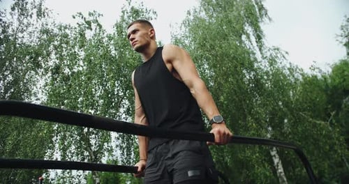 Fit Man Exercising on Metal Bar Outdoors