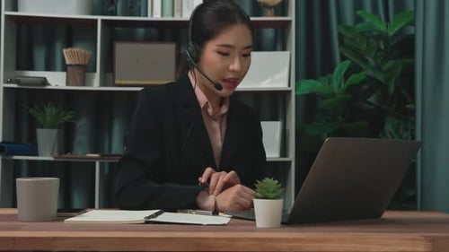 Woman working from home on computer and writing