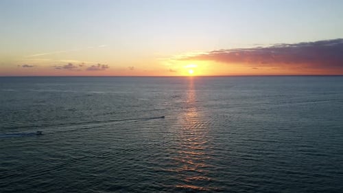 Beautiful following drone shot of sunrise over the Atlantic Ocean with 2 boats in the distance headi