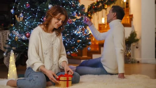 Romantic Couple Decorating Christmas Tree and Wrapping Gifts