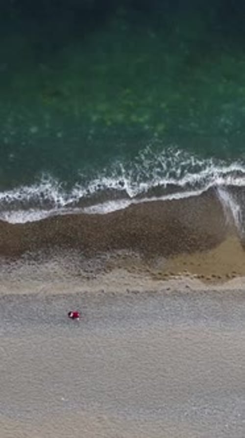 Aerial Vertical View of Beach with Wave Caressing Shore Sun Glare Small Waves on the Water Surface