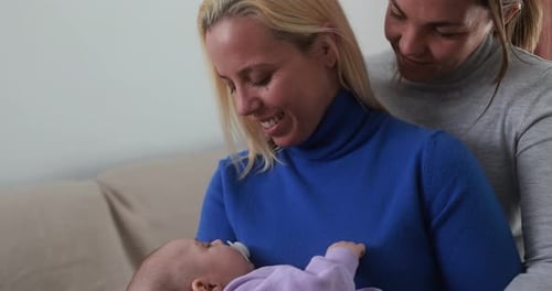 Female gay couple having tender moment with their baby son at home - Family, lgbt and love concept