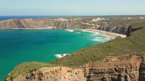 Aerial: The town of Arrifana with people surfing.