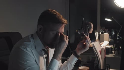 Tired Businessman Working on Computer at Night in Office