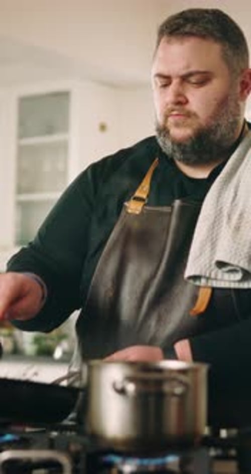 Man Cooking at Gas Stove in Bright Kitchen