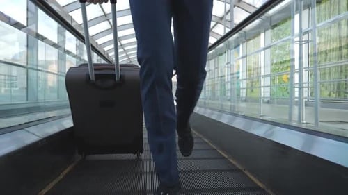 Legs of Businessman Running on Escalator in Hall of Terminal
