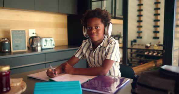 Homework, headphones and face of child with notebook writing for ...