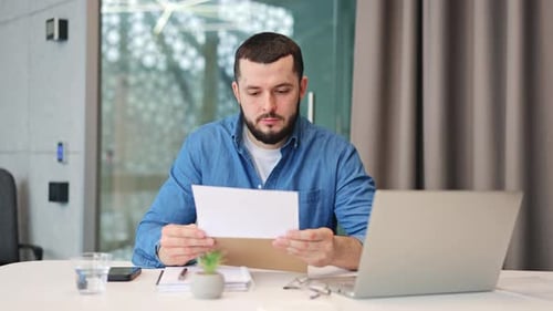 Happy Man Reacts to Good News Letter in Modern Office