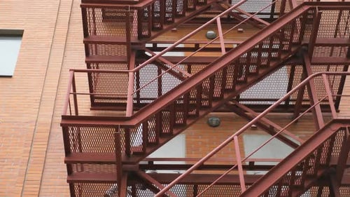 Man Walks Down Fire Escape in Urban Setting
