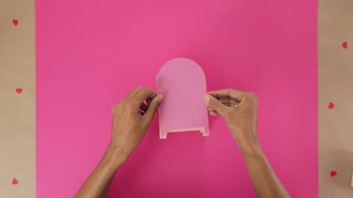 Hands Assembling a Pink Paper Heart Card