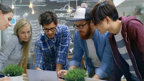 Diverse team collaborates over laptops at workplace