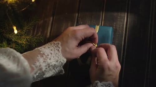Hands Tying Ribbon on Christmas Present
