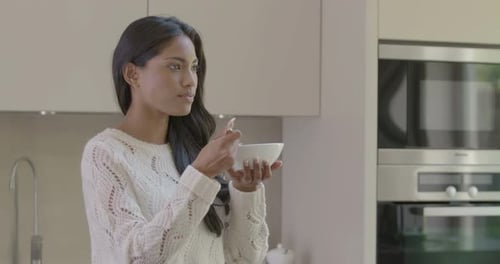 Woman Eats Yogurt in Modern Kitchen