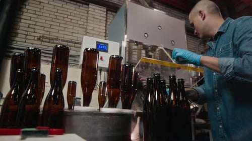 Worker Places Bottles on Industrial Filling Machine