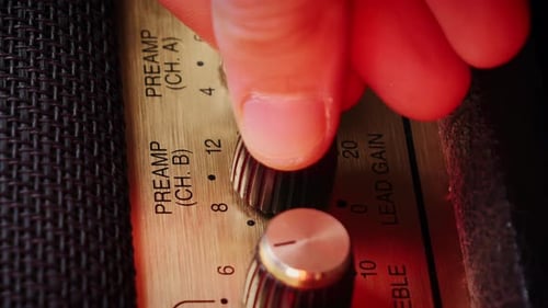 Hand Adjusting Knobs on Vintage Amplifier Close-Up