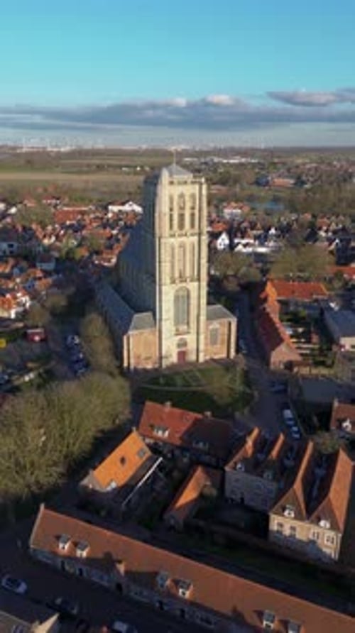 Aerial view of a historic town with a tall Gothic church in the center. Red-roofed houses