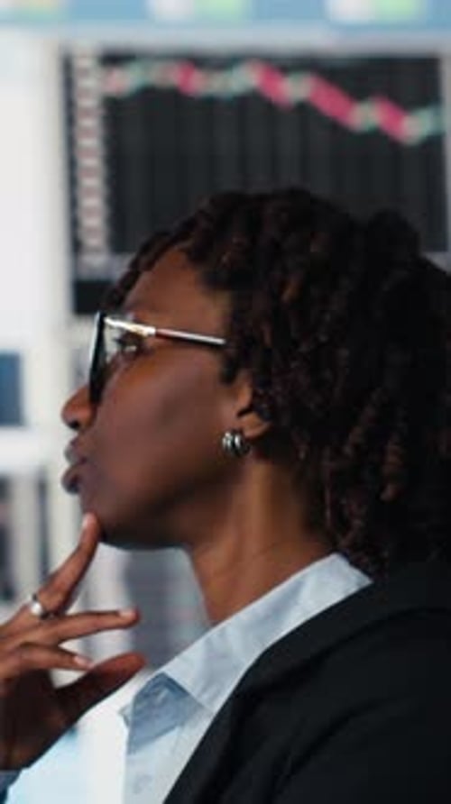 Vertical Video Close Up of Management Executive Comparing Company Metrics on Digital Videowall