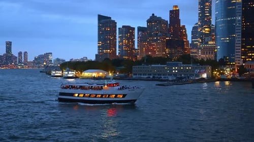 Dinner cruise ship sailing near Manhattan skyline at dusk.