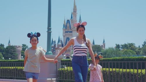 Asian mother and adorable kid daughters walking at the theme park.