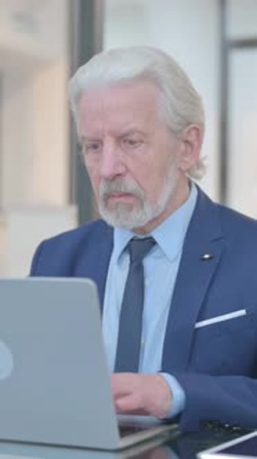 Old Businessman Working on Laptop in Office, vertical video