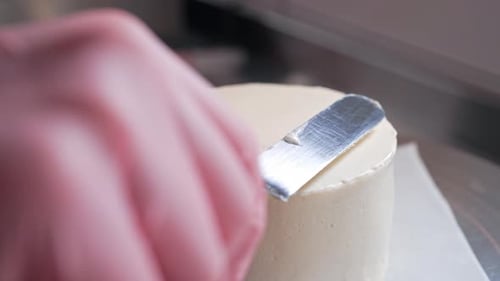 Gloved Hand Frosting a Cake Close Up