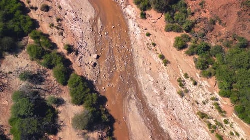 Aerial top view drone flying over red river and arid desert.