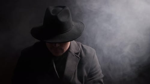 Man wearing stylish hat on black background with smoke
