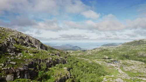 Drone Panning Left Over Lush Green Rugged Mountain Under Cloudy Blue Sky
