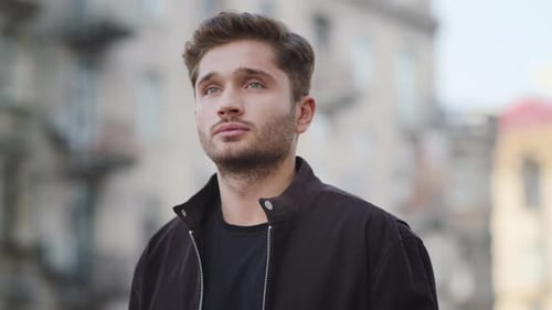 Pensive Hipster Guy Waiting for Call to Mobile Phone on City Street