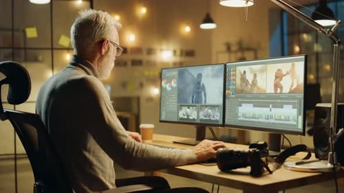 Evening in Creative Office: Professional Middle Aged Videographer Works on Desktop Computer, Doing
