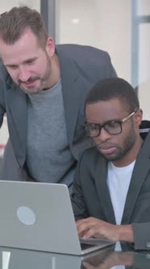 Two Men Working Together on Laptop in Office
