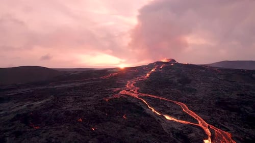 Epic Beautiful Sun Setting Erupting Volcano. Rivers of Magma Flows Across Black Hardened Lava Field.