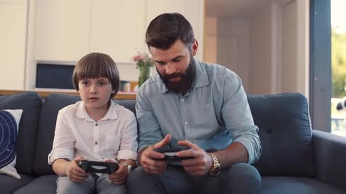 Father and Son Play Video Games Together at Home