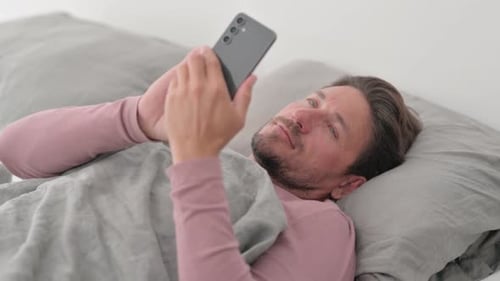Man Lying in Bed Using Smartphone