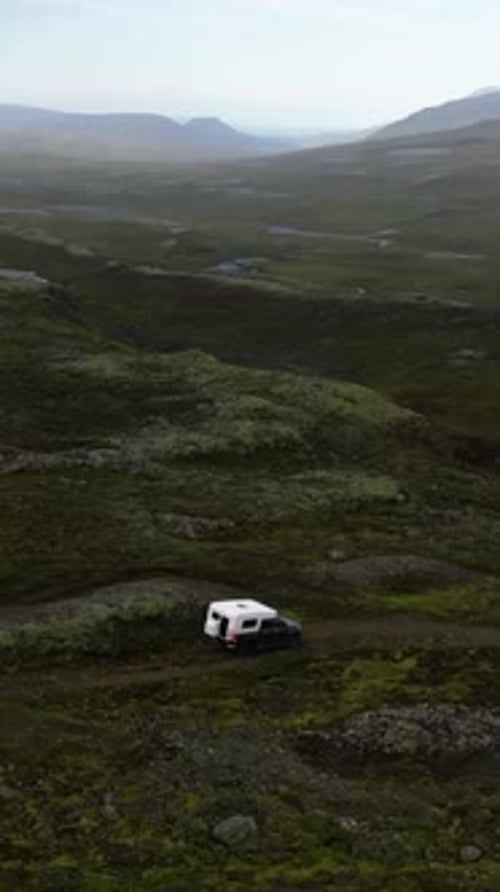 Vertical drone shot around a camper truck, driving in the wilderness of Iceland