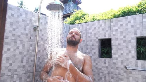 Man Enjoying Refreshing Shower in Outdoor Tropical Setting