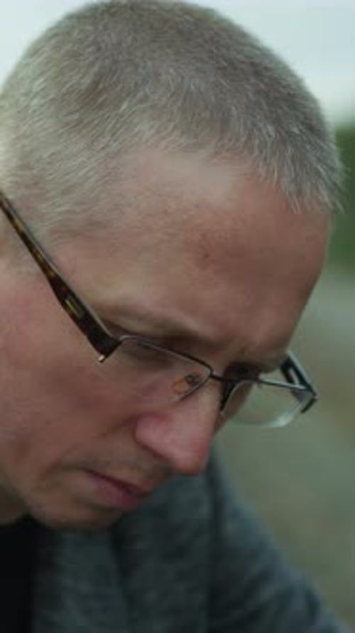 Contemplative Man in Gray Jacket Looking Down Outdoors