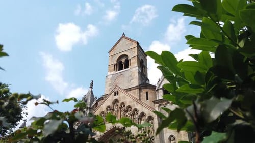4K Ancient church in the centre of a beautiful park by day. White clouds are slowly moving in the ba