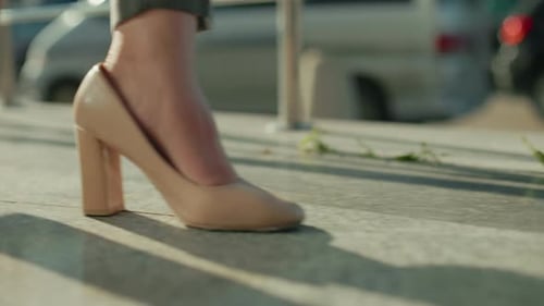 Side View of Woman Walking in Heels Casting Shadow with Cars in Background