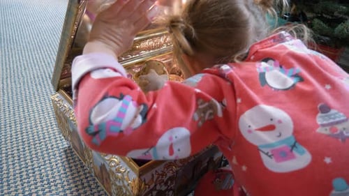 Child Exploring a Christmas Ornament Box