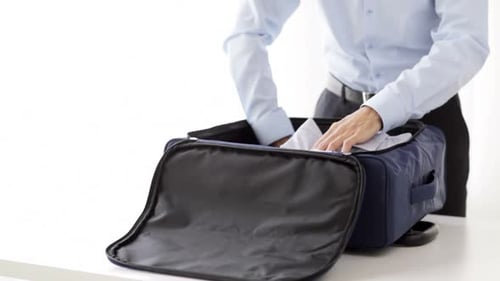 Man packing clothes into luggage, ready to travel