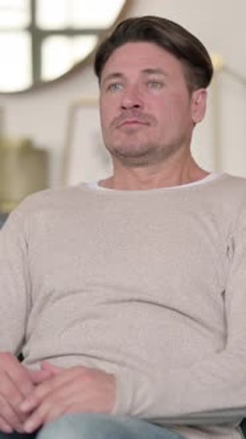 Man Sitting, then Standing in Interior Setting