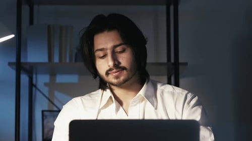 Tired Man Rubbing Eyes at Desk with Laptop