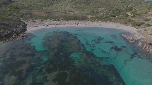 Aerial Drone Zooms Out Turquoise beach water bay at Cala Sa Torreta Spain Travel Destination, natura