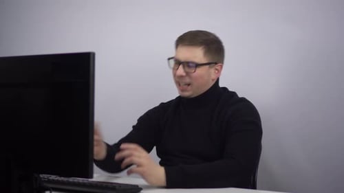 A Young Man Looks at a Computer Monitor and Laughs Emotionally