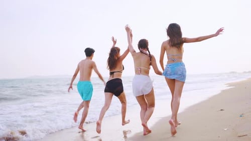 Group of Asian man and woman running on the beach during summer time.