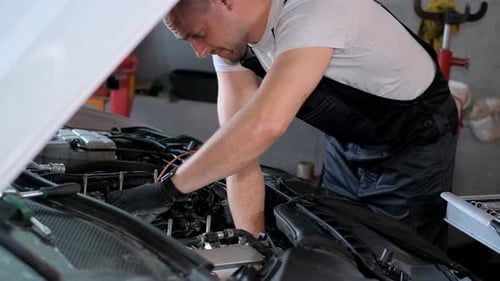 Mechanic Under Vehicle Hood in Garage Working on Automotive Engine